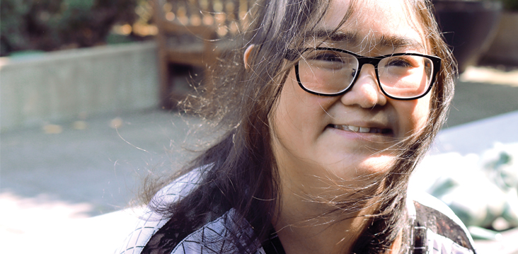 Woman wearing glasses looking at the camera smiling.