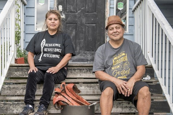 Indigenous man and woman sitting on stairs.