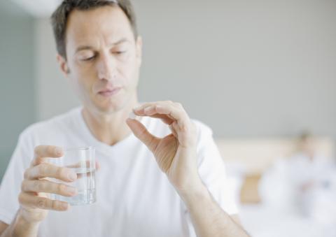 Man Holding Medication and Glass of Water